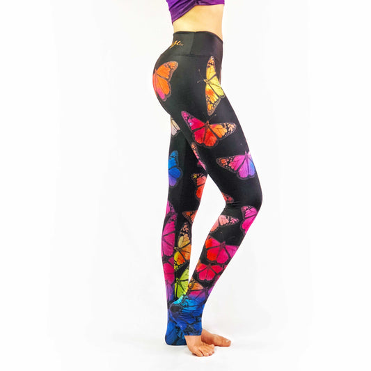 Woman wearing black leggings with rainbow butterfly print leggings.