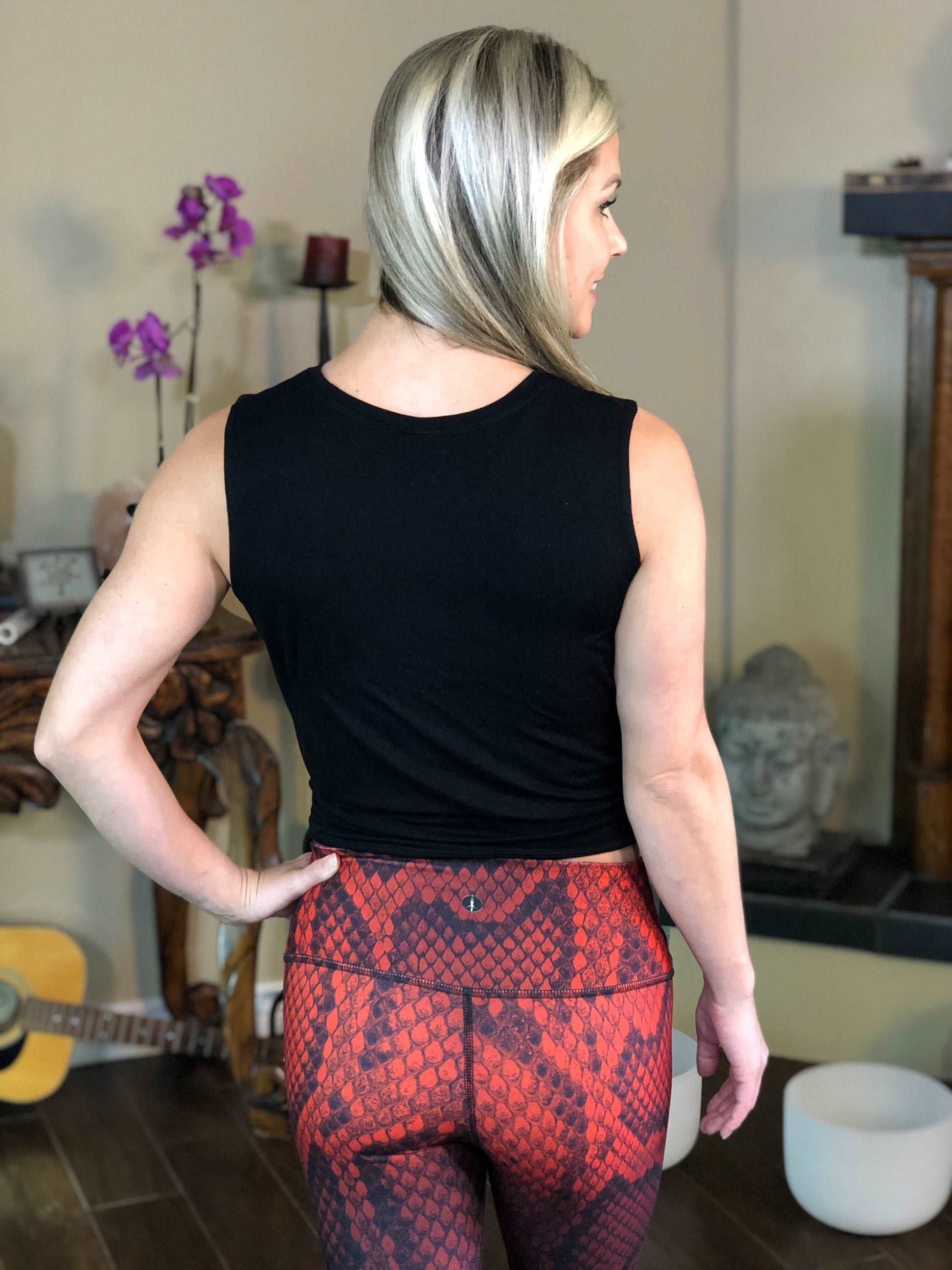 Woman wearing black tie-front tank top with geometric flower on it.