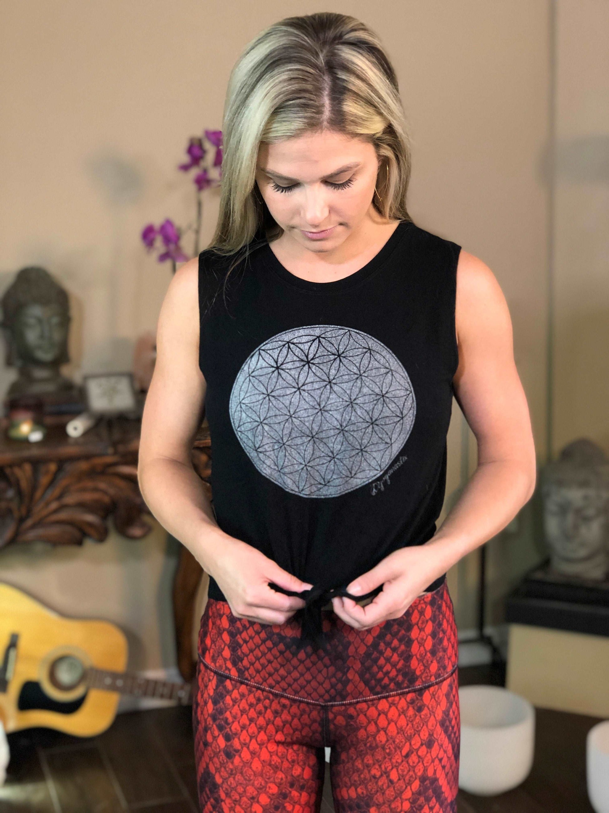 Woman wearing black tie-front tank top with geometric flower on it.